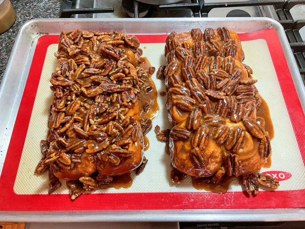 Two delicious pecan rolls sitting side by side on a baking sheet, ready to be devoured!