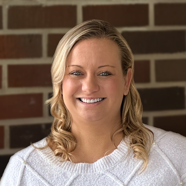 Natalie Main, Senior Living Director at The Boulevard Senior Living of Saint Charles, smiling outdoors while standing against a brick wall in a light sweater.