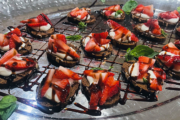 A platter of dessert bites at The Boulevard St. Charles, featuring soft cheese and fresh strawberries.