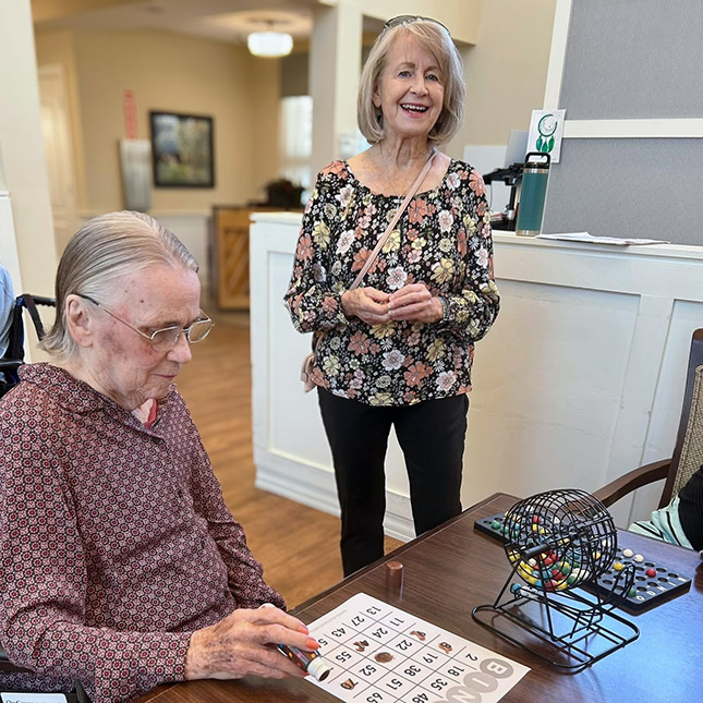 A woman smiles while a senior resident plays a game of Bingo at The Boulevard Senior Living of St. Charles.