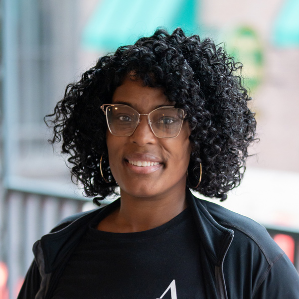 Trneal Reading, Memory Care Director at The Boulevard Senior Living of Saint Charles, smiling in a professional headshot, wearing glasses and a black top, with a softly blurred outdoor background featuring railing and architectural details.