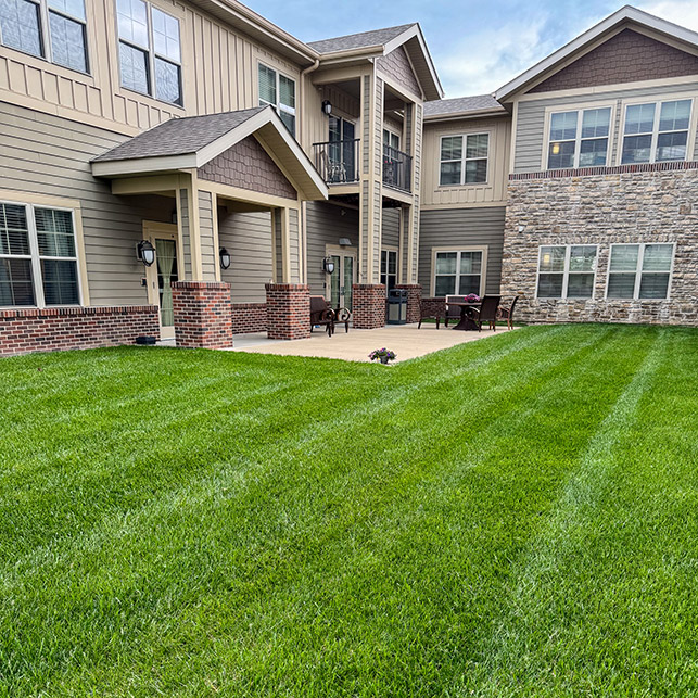 The exterior of The Boulevard Senior Living of St. Charles, featuring bright green, freshly landscaped lawn.