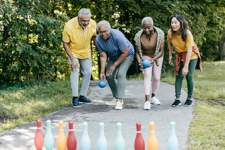 Diverse group of senior adults playing outdoor lawn bowling on a sunny day